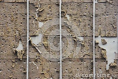 Wall surface of a being demolished building and worn insulation material and plastic pipes on it. Stock Photo