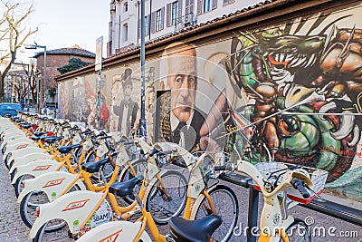 Walls artistics graffitis and bicycles station in Milan, Italy Editorial Stock Photo