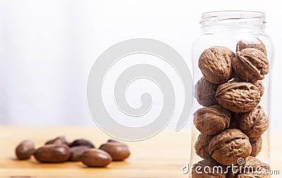 Walnuts glass jar and pecan over wooden surface Stock Photo