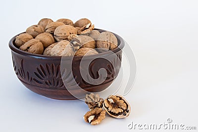 Walnuts lie in a bowl, chopped nuts nearby, on a white background Stock Photo