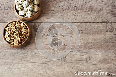 Walnuts and quail eggs in wooden bowls. Rustic wooden background, diffused natural light. Protein nutrients. Stock Photo