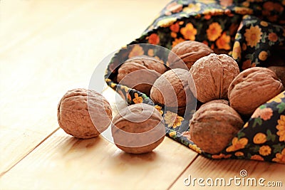 Walnuts scattered from a bag on sunlit light brown wooden floor Stock Photo