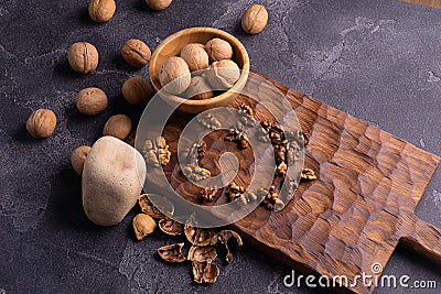Walnuts in wooden bowl on wooden carved board. Walnuts, stone and cutting board. Healthy nuts and seeds composition. Stock Photo