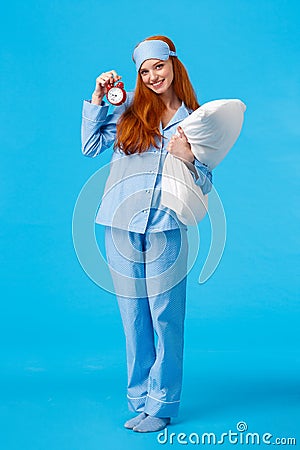 Wanna go bed. Pretty coquettish and silly european feminine redhead teenage girl with red alarm clock holding pillow Stock Photo