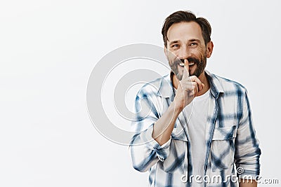 Wanna hear secret. Portrait of excited handsome adult man with beard and moustache smiling joyfully while making shush Stock Photo