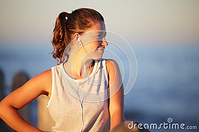 Want to enjoy exercise more Creative a workout playlist. a sporty young woman wearing earphones while out for a run. Stock Photo