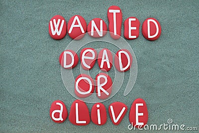 Wanted, dead or alive, creative slogan composed with red colored stone letters over green sand Stock Photo