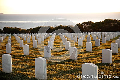 War cemetery with rows of white marble graves on green grass at sunset with ocean view. Marine veteran's cemetery Editorial Stock Photo