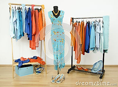 Wardrobe with complementary colors orange and blue clothes arranged on hangers. Stock Photo