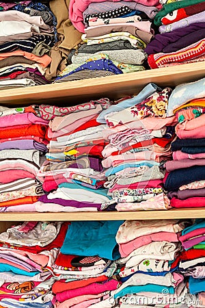 A wardrobe full of childrens clothes creative background texture. Lots of rows of colorful kids clothing laying neatly aligned Stock Photo