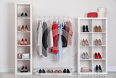 Wardrobe shelves with different stylish shoes and clothes indoors Stock Photo