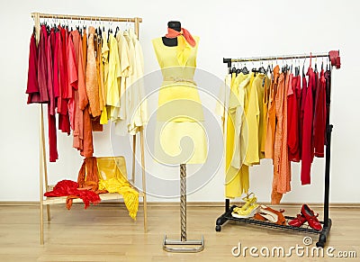 Wardrobe with yellow, orange and red clothes arranged on hangers. Stock Photo