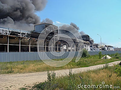 Warehouse fire with black thick smoke against a clear sky. Sandwich panels are burning Stock Photo