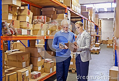 Warehouse, man and woman with tablet, supply chain and inventory with cooperation and industrial. Clipboard, supervisor Stock Photo