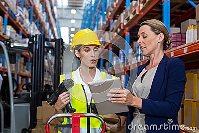 Warehouse manager with interacting female worker over digital tablet Stock Photo