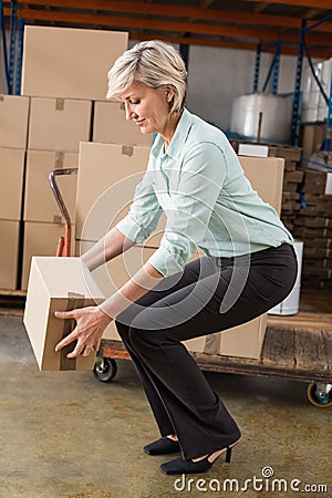 Warehouse manager picking up cardboard box Stock Photo