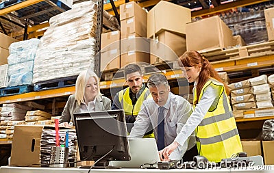 Warehouse managers and worker working on laptop Stock Photo