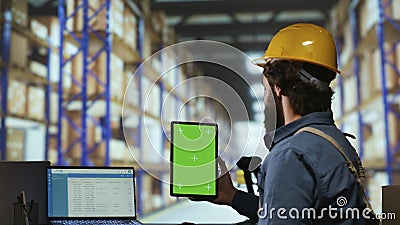 Warehouse operator holds greenscreen on tablet Stock Photo