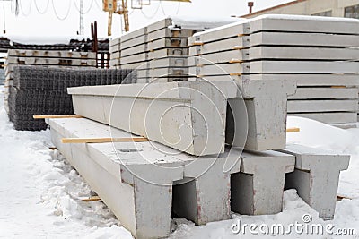 Warehouse for reinforced concrete products in winter. Reinforced concrete foundation beams for building construction. Stock Photo