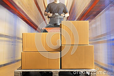 Warehouse worker driving electric forklift pallet jack unloading shipment pallet good Stock Photo