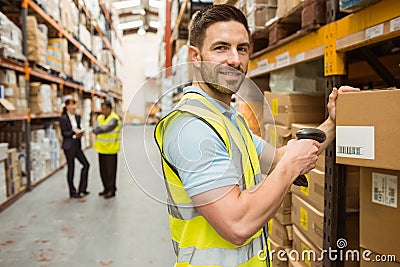 Warehouse worker scanning box while smiling at camera Stock Photo