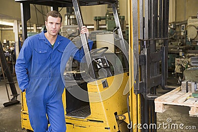 Warehouse worker standing by forklift Stock Photo