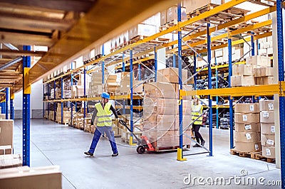 Warehouse workers pulling a pallet truck. Stock Photo