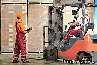 Warehousing and storage. warehouse workers works with forklift loader Stock Photo