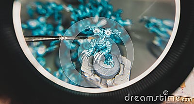 Magnifying glass lens view of miniature painting progress with brush Editorial Stock Photo