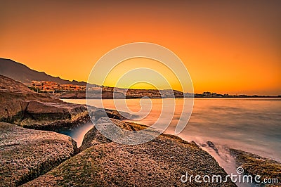 Warm colors at an impressive sunrise on stones nearby the sea. Stock Photo