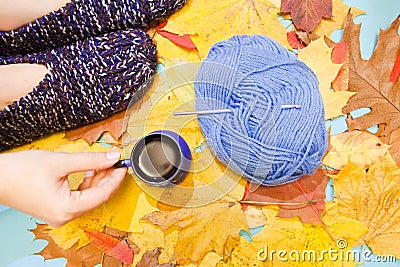 Warm comfortable knitted slippers, a hand holding a cup of hot coffee, and a ball of woolen or cotton yarn with crochet hook Stock Photo