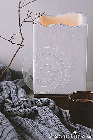 Warm and cosy home with cup of coffee, concrete lampe and rustic wool plaid Stock Photo