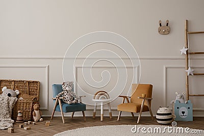 Warm and cozy kids room interior with orange and beige armchair, white stool, round rug, plush toys, wooden blockers, beige wall Stock Photo