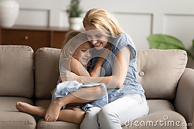 Little daughter and young mommy hugging on couch Stock Photo