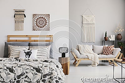 Warm ethno bedroom with comfortable king size bed, elegant settee and macrame on the wall Stock Photo