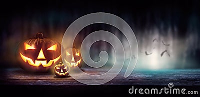 Warm glow of Jack O` Lanterns on a wood bench Stock Photo