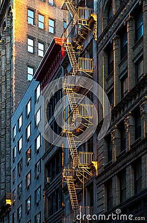 Warm glow of sunlight shining on a fire escape on the front of a Stock Photo