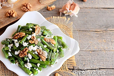 Warm green bean salad recipe. Balsamic green beans salad with creamy cheese, crunchy walnuts, garlic and spices on a plate Stock Photo