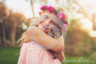 Warm hugs for my feline friend. a happy little girl holding a kitten and looking at the camera outside in the nature. Stock Photo