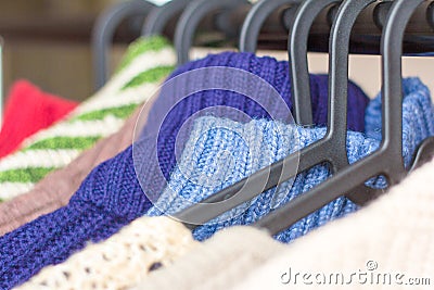 Warm knitted things, sweaters and dresses hang on hangers Stock Photo