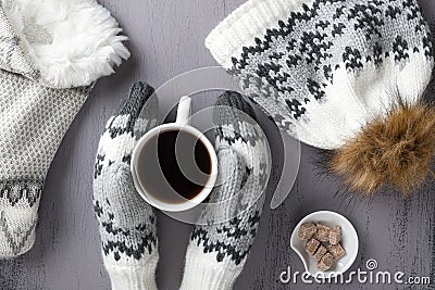 Warm knitwear: mittens, hat, scarf and cup of coffee on a gray rustic wood background. Winter cozy still life. Top view Stock Photo