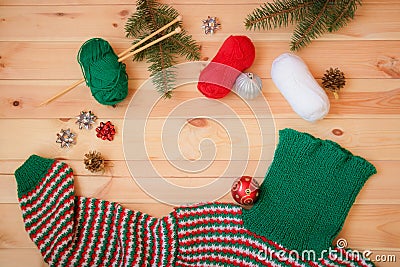 Warm red, green and white homemade knitted sweater, fir branches and christmas balls Stock Photo