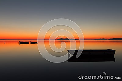 A warm sunset on a calm water, with Islands in the background Stock Photo