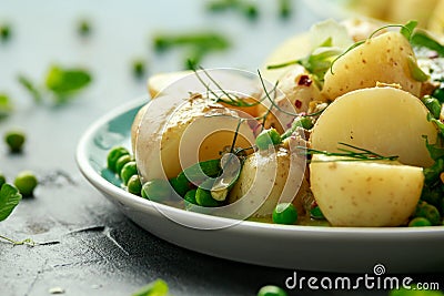 Warm vegetarian new baby potato salad with petit pois peas, Dijon mustard and capers dressing, served with fresh dill Stock Photo