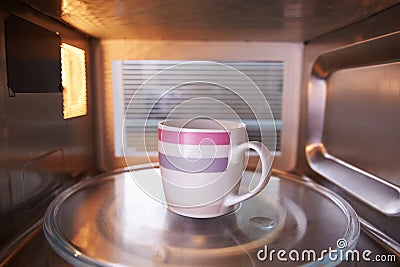 Warming Cup Of Coffee Inside Microwave Oven Stock Photo