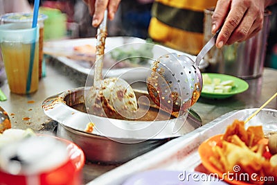 Warming satay sauce in the pot. Satay is a dish of skewered grilled meat with Javanese origins in Malacca City, Malacca, Malaysia Stock Photo
