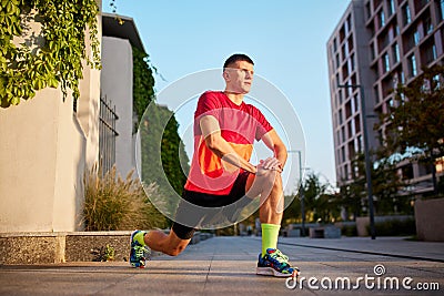 Warming-up muscles exercises before training. Man in sportswear, running athlete doing ATG split squat before training Stock Photo