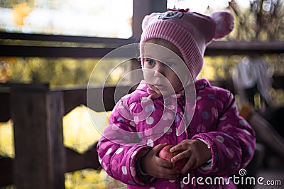 Warmly dressed little girl with a red fresh apple. Stock Photo