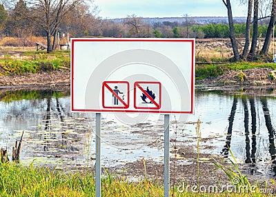 Warning banner on the shore of the pond with inscriptions prohibiting Smoking and bonfire in nature without text. Stock Photo