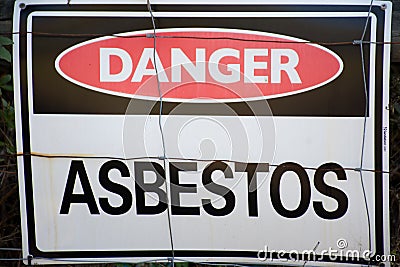 A warning sign Danger Asbestos on a fence at site rehabilitated post asbestos contamination Stock Photo